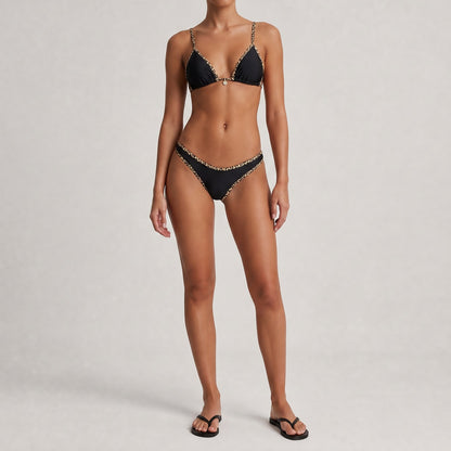 Alessandra bikini set in black, white, and cream featuring leopard print contrast piping and a gold sun charm detail.