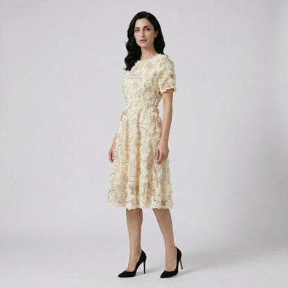 Front view of the Cindi champagne midi dress featuring white 3D fabric roses and rose gold sequin detailing on a white faux fur rug.