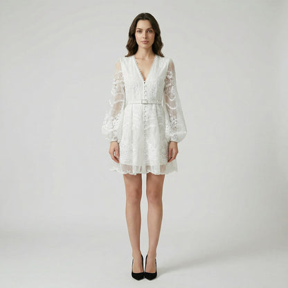 White floral lace mini dress with long puff sleeves and pearl buttons on a flat lay background