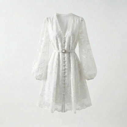 White floral lace mini dress with long puff sleeves and pearl buttons on a flat lay background