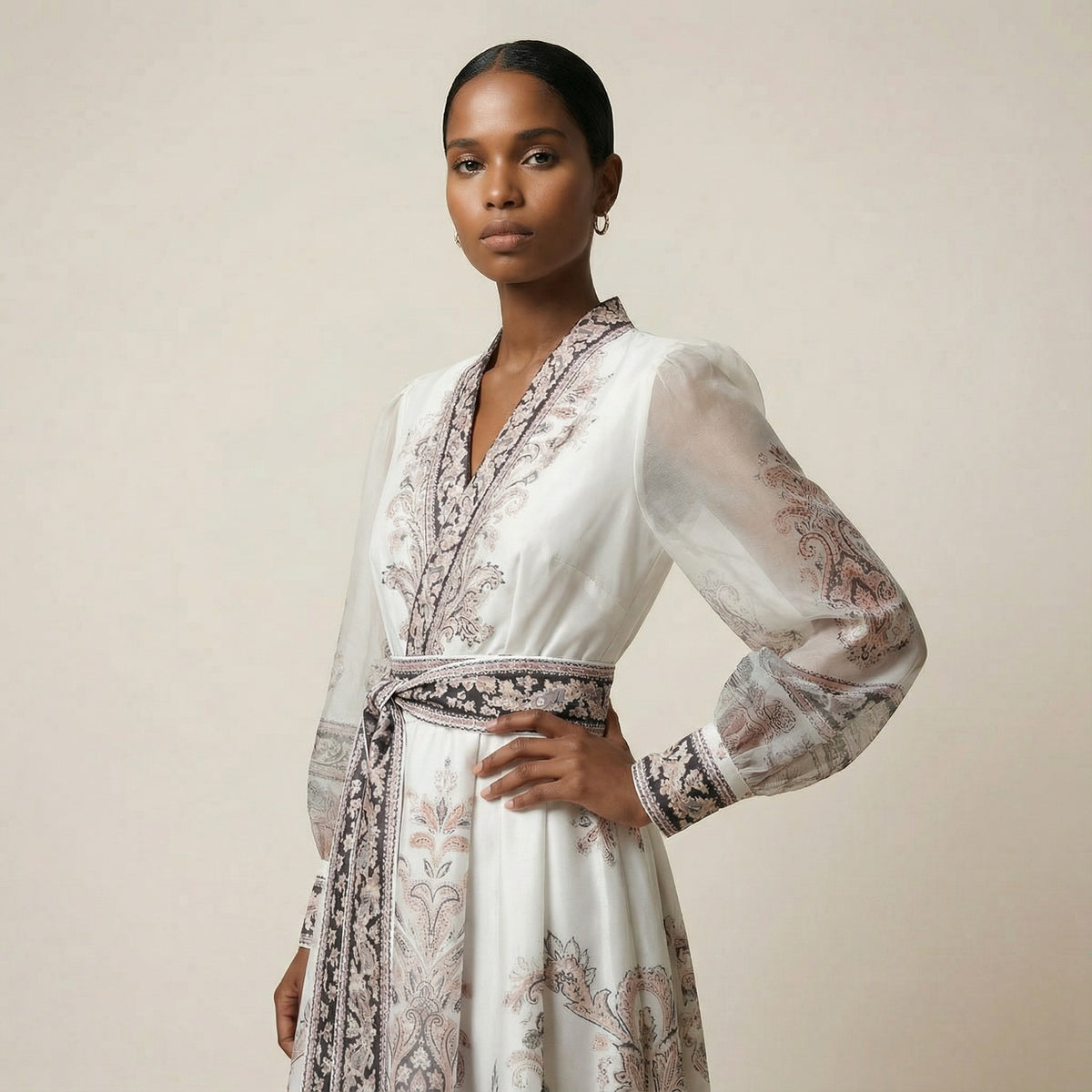 A woman modeling the Gabriella black ribbed knit maxi dress featuring a long-sleeve bodice and a side-pleated accordion skirt with a white and orange sunset ombré design.