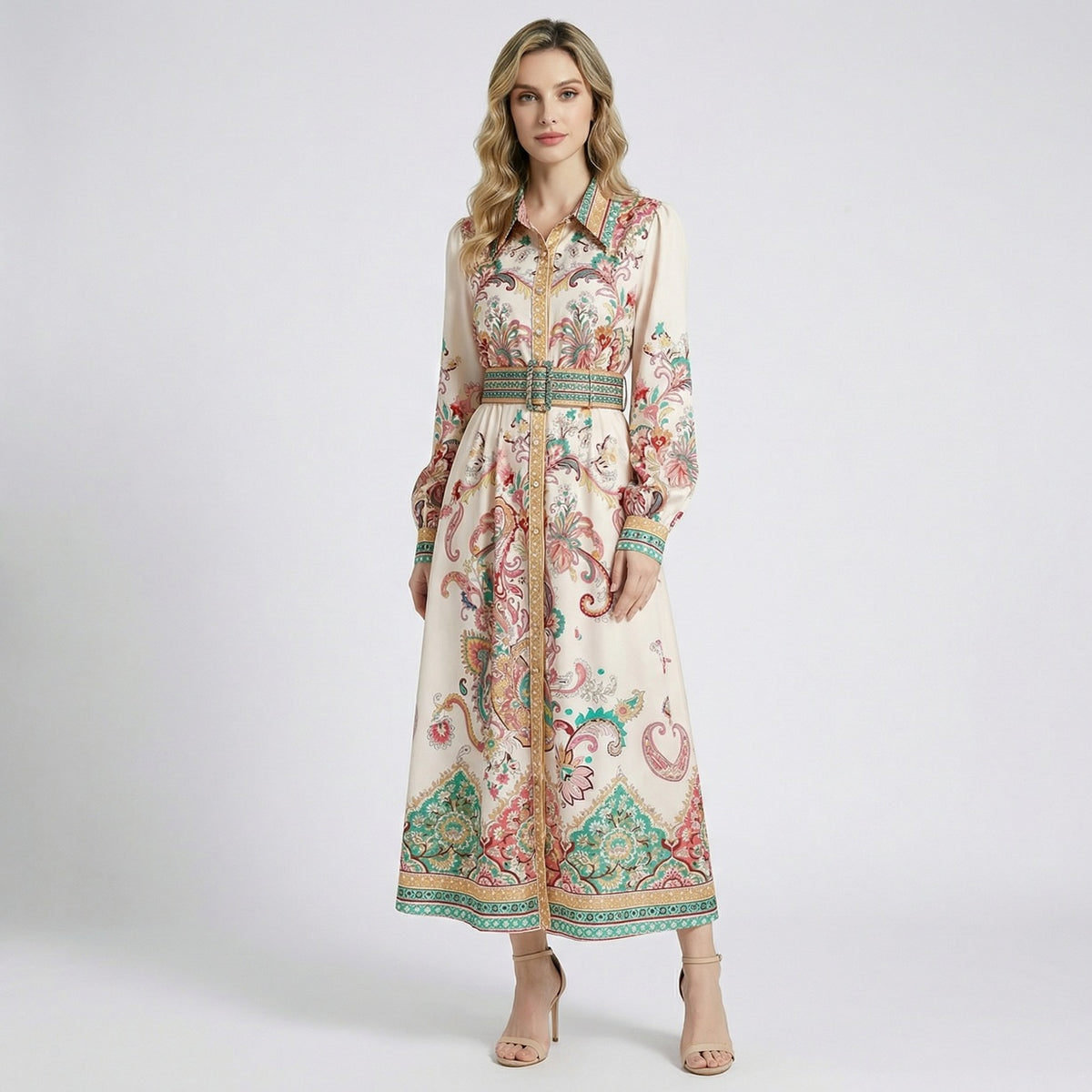 Front view of a woman wearing the Gail maxi dress, a cream-colored long-sleeve shirt dress with teal and coral paisley patterns and a matching belt.