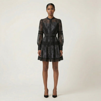 The Graciana dress in white and black featuring sheer floral embroidery, lattice lace panels, long puff sleeves, and a matching belted waist.