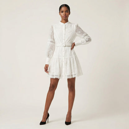 The Graciana dress in white and black featuring sheer floral embroidery, lattice lace panels, long puff sleeves, and a matching belted waist.