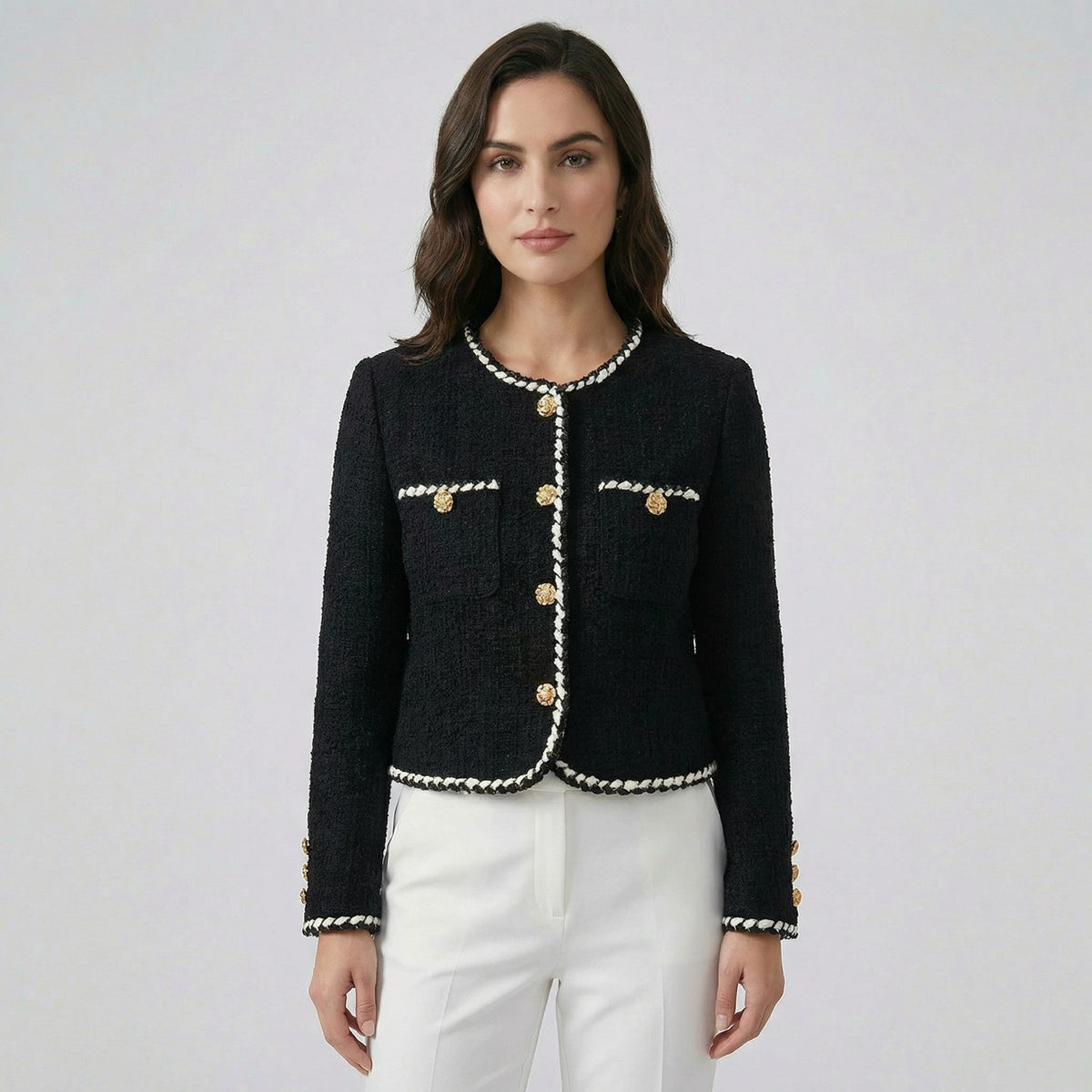 Flat lay of Louise black tweed jacket with white braided trim and gold floral buttons.