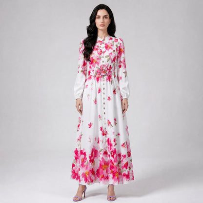 Louise Dress showcasing the vibrant pink floral placement motif along the hem and shoulders of the white maxi gown. Louise Dress, a blue and white floral maxi dress with a mock neck, button-down front, and a matching waist belt.
