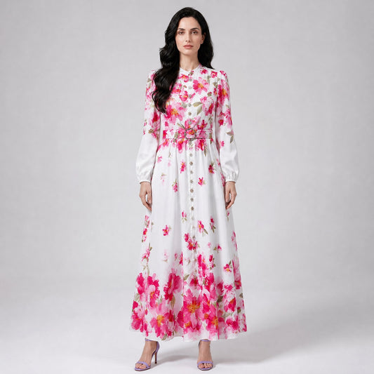Louise Dress showcasing the vibrant pink floral placement motif along the hem and shoulders of the white maxi gown. Louise Dress, a blue and white floral maxi dress with a mock neck, button-down front, and a matching waist belt.