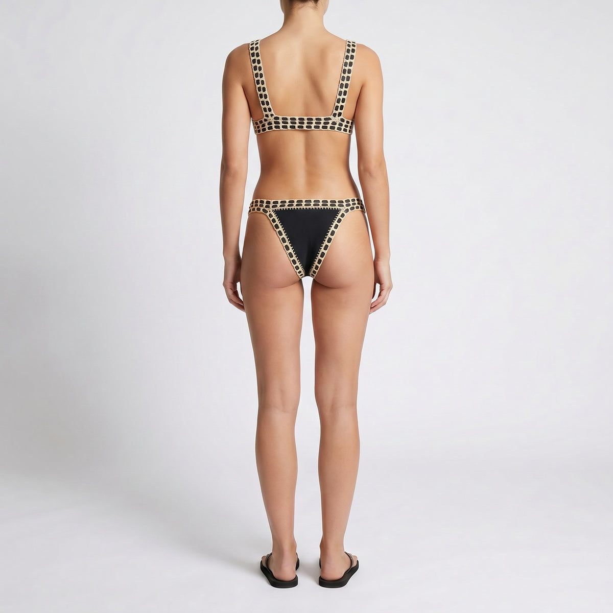 Flat lay of Lumi crochet-trim bikini set in multiple colors including purple, black, and white with artisanal hand-stitched detailing on a stone background.