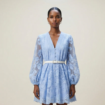 woman modeling the Nadia ribbed knit mini dress featuring a long-sleeve bodice and a side-pleated accordion skirt panel.