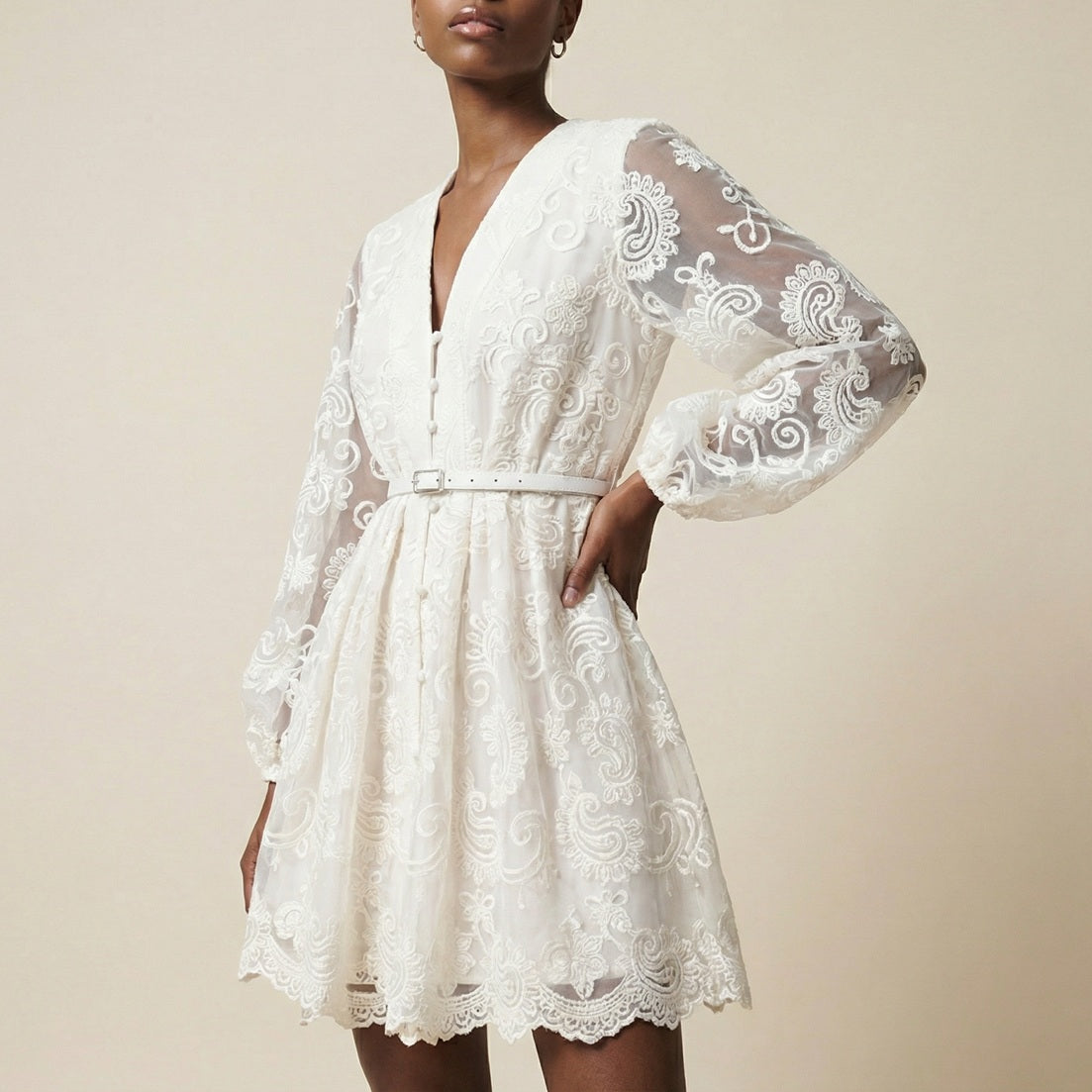 woman modeling the Nadia ribbed knit mini dress featuring a long-sleeve bodice and a side-pleated accordion skirt panel.