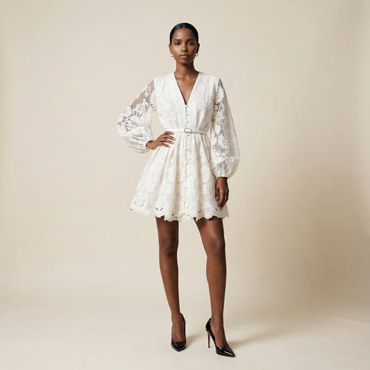 woman modeling the Nadia ribbed knit mini dress featuring a long-sleeve bodice and a side-pleated accordion skirt panel.