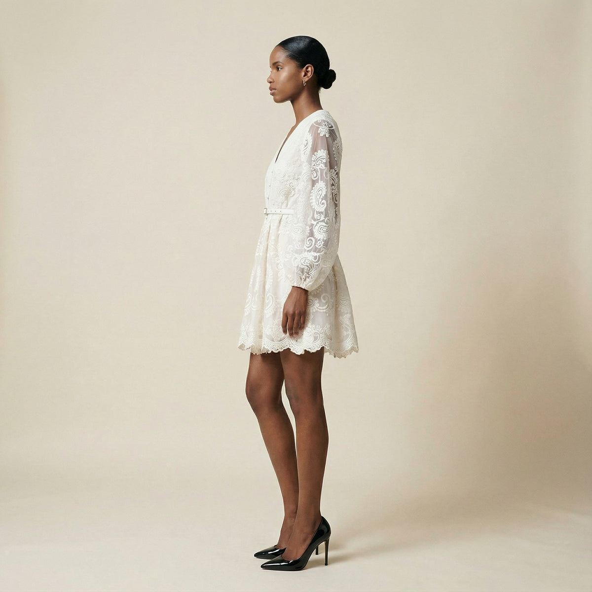 woman modeling the Nadia ribbed knit mini dress featuring a long-sleeve bodice and a side-pleated accordion skirt panel.