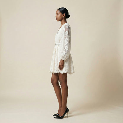 woman modeling the Nadia ribbed knit mini dress featuring a long-sleeve bodice and a side-pleated accordion skirt panel.