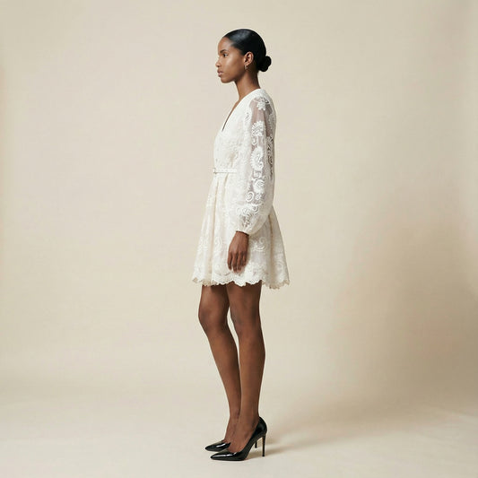 woman modeling the Nadia ribbed knit mini dress featuring a long-sleeve bodice and a side-pleated accordion skirt panel.