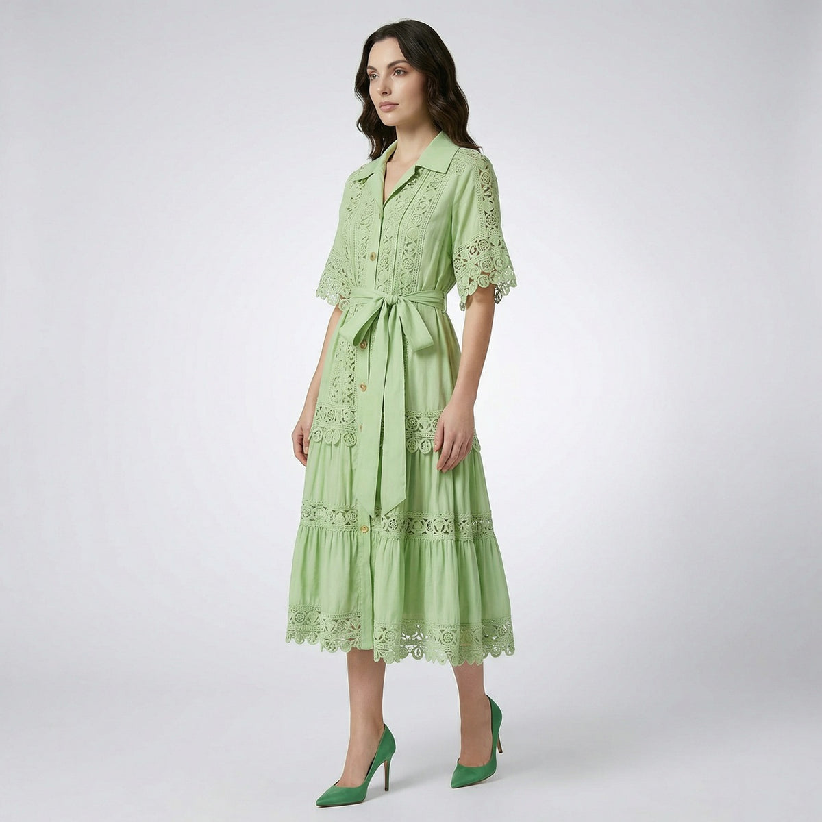 The Noora midi dress shown in black, white, sage green, and camel featuring intricate lace panels, gold buttons, and a matching belt.