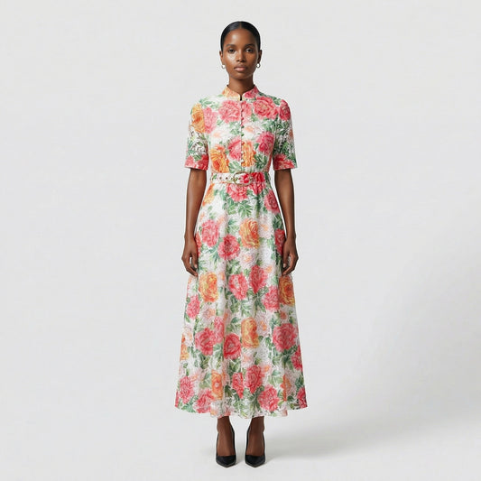 Full length view of the rhona white guipure lace maxi dress with red and orange floral embroidery and matching belt on a grey background.