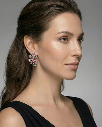 Pair of Teodora statement fan-shaped earrings featuring pink, fuchsia, and emerald green AAA+ cubic zirconia stones on a gold-tone background on woman.